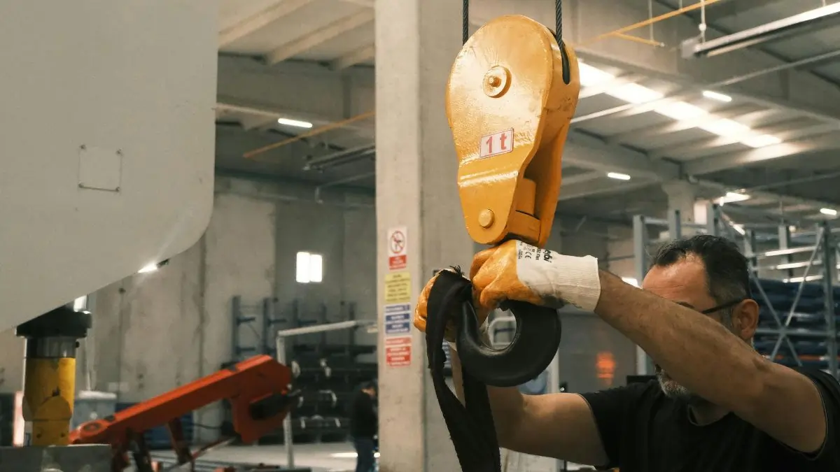 Worker preparing lifting hook for equipment testing in an industrial workshop – Industrial Lifting Ltd UK
